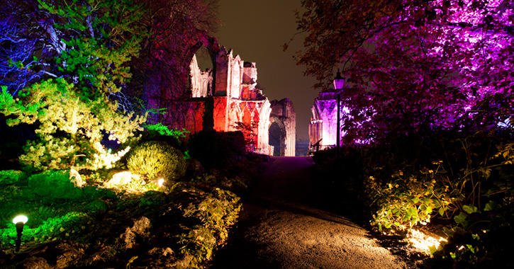 View of gardens and castle illuminated in different colours as part of a outdoor light trail